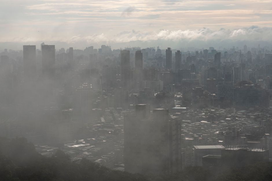 A panoramic view of a densely populated city with a visible layer of smog or haze over the buildings, suggesting poor air quality and potential allergens.