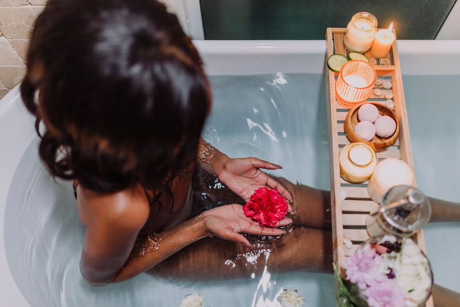 A warm bath filled with water, floating lavender sprigs, and a small wooden scoop of Epsom salts on the edge, representing a relaxing pre-sleep ritual.
