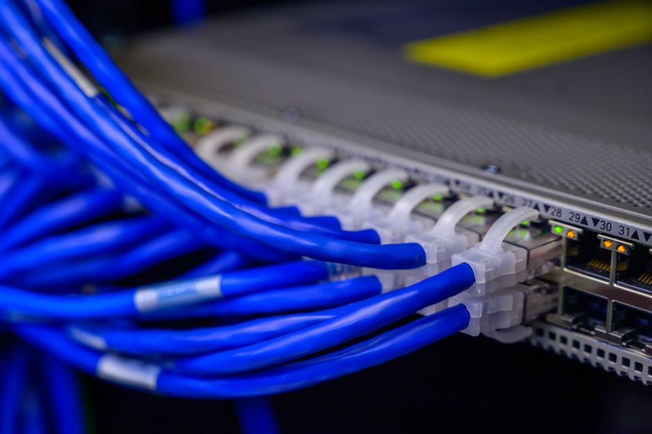 A close-up of an Ethernet cable plugged into a gaming console with a controller nearby, emphasizing a wired connection.