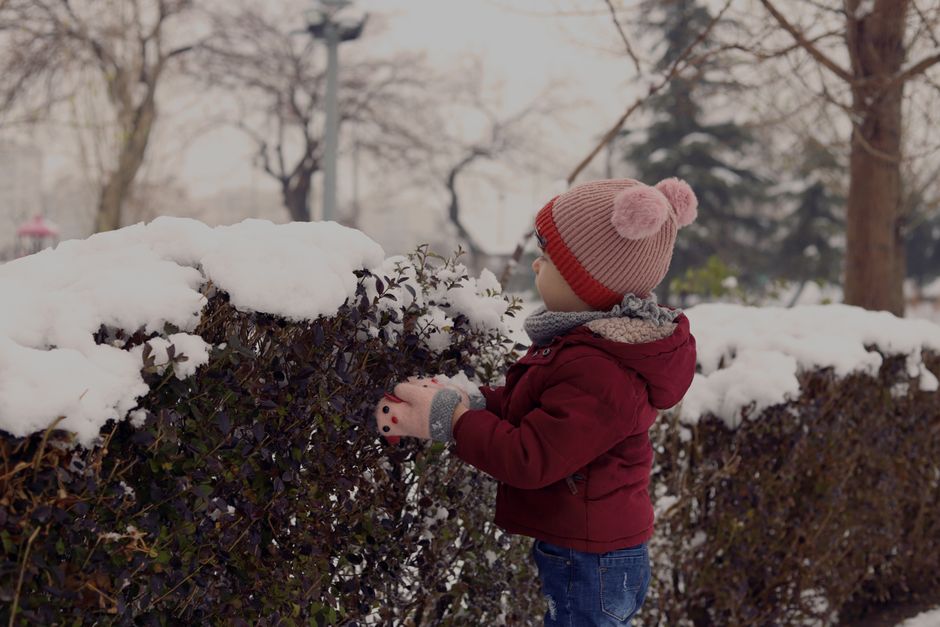 A family, including a child, adjusting their layered clothing in an outdoor setting, demonstrating adaptability to changing weather conditions.